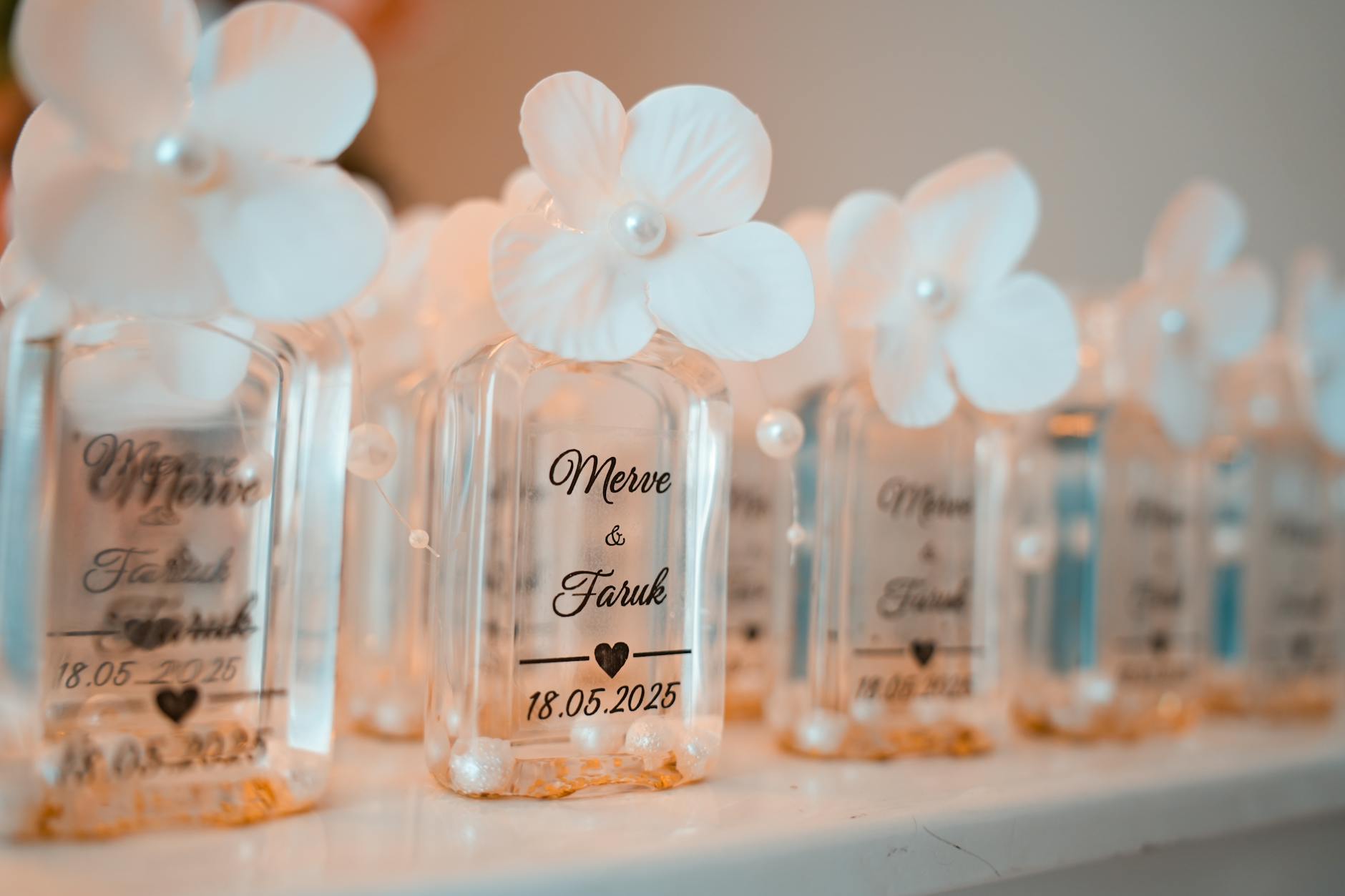 Close-up of elegant personalized wedding favor bottles with flowers and text.