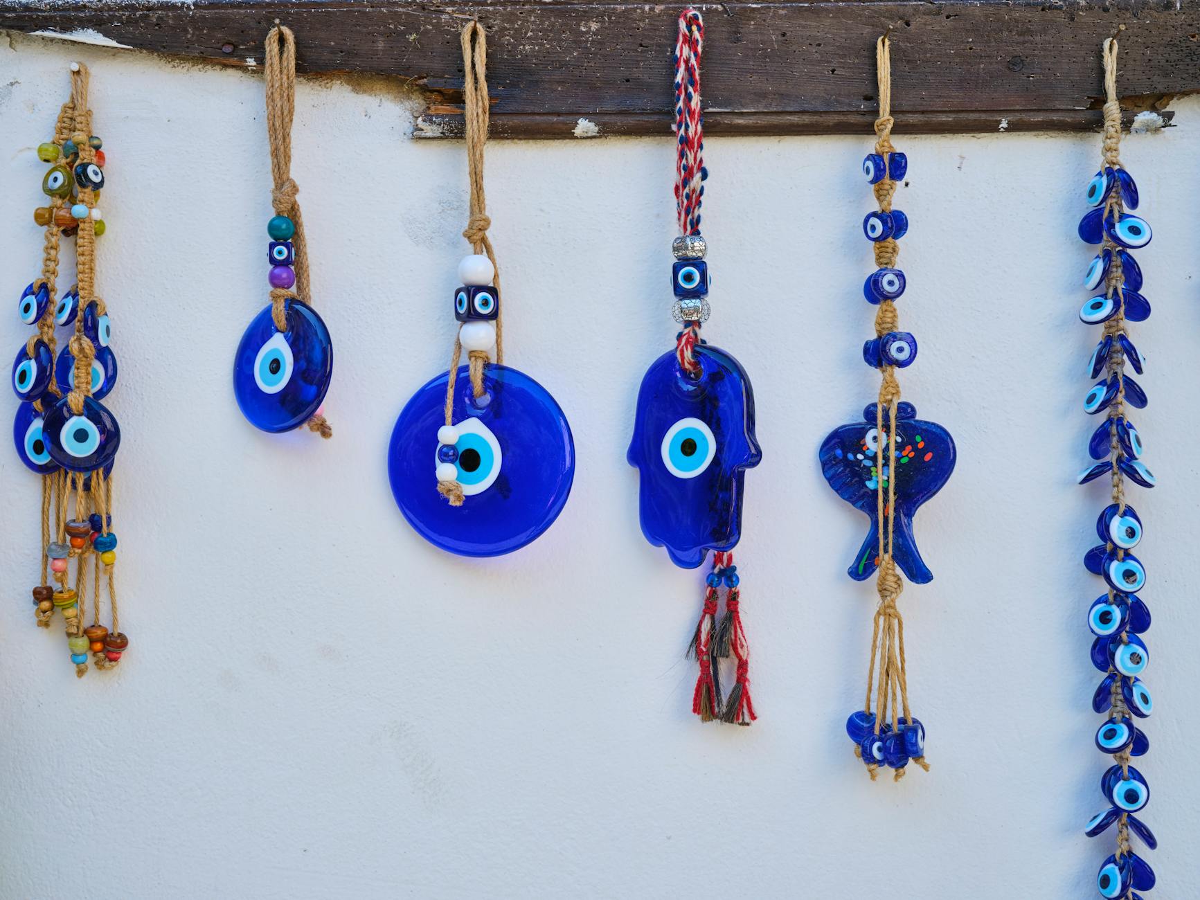 Colorful handmade evil eye wall decorations hanging on a white wall.